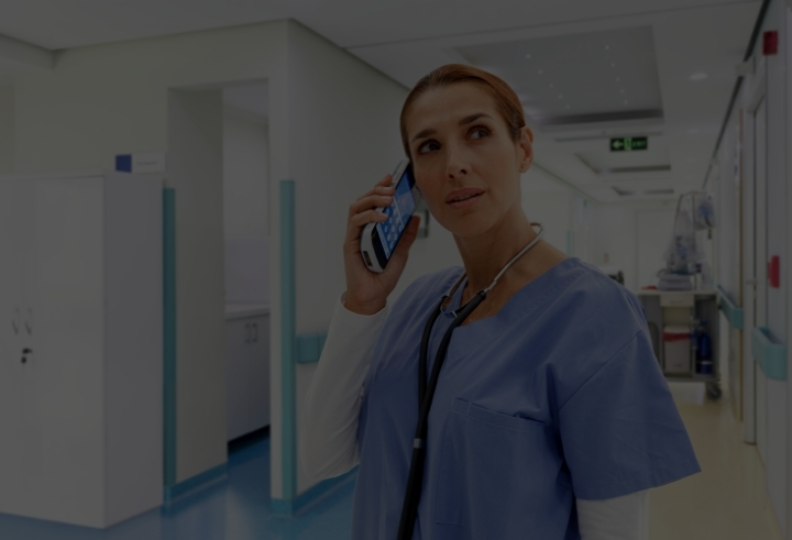 Female medical professional holding connectivity mobile device to ear in a hospital setting